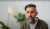 thumb-Maksym Nefyodov in a cardigan in a bright room with plants and a lamp