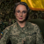 thumb-Valeria Skrypnikova in military uniform against the background of a camouflage net and the Ukrainian flag